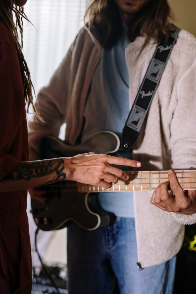 Person getting instructions on how to play a guitar